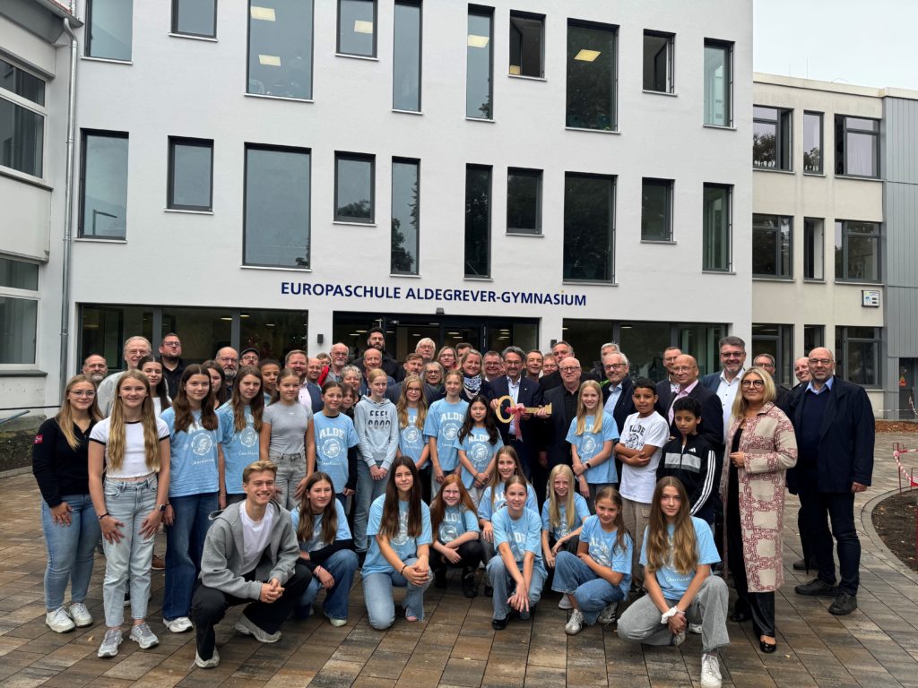 Gruppe Menschen vor dem Aldegrevergymnasium bei der offiziellen Eröffnung der Erweiterung des Gebäudes